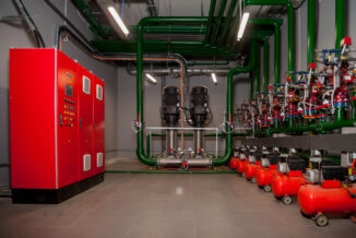 Industrial interior of water pump, valves, pressure gauges, motors inside engine room. Valve and pumps in an industrial room. Urban modern powerful pipelines and pumps, automatic control systems